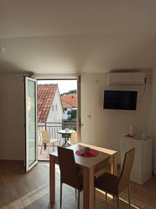 Lastva Holliday Rooms في بودفا: غرفة معيشة مع طاولة وكراسي وشرفة