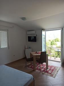 a living room with a table and chairs and a balcony at Lastva Holliday Rooms in Budva