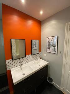 a bathroom with two sinks and an orange wall at Quiétude en hyper-centre in Blois
