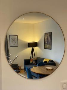 a mirror reflecting a living room with a couch and a table at Quiétude en hyper-centre in Blois