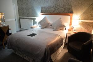 a hotel room with a bed and a chair at Lauriston & Lawton Court Hotel in Llandudno