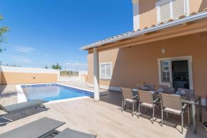 eine Terrasse mit Tisch und Stühlen neben einem Swimmingpool in der Unterkunft Villa Ribeiro By Keys to Algarve in Armação de Pêra