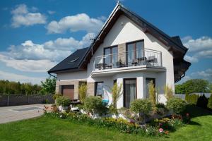 une maison blanche avec un balcon et des fleurs dans l'établissement Pokoje Jelonek, à Władysławowo