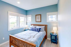 a blue bedroom with a bed and two windows at Seaside Refresh in Seaside