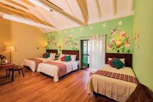 two beds in a room with green walls at ANAHUARQUE Hotel Boutique in Cusco