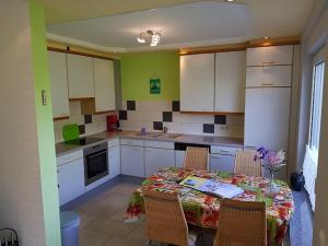 a kitchen with a table with chairs and white cabinets at Haus Christine in Wremen