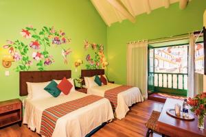 a bedroom with two beds with flowers on the wall at ANAHUARQUE Hotel Boutique in Cusco