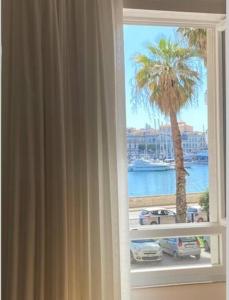 okno z palmą i widokiem na wodę w obiekcie Ortigia Riflessa - design e comfort vista mare w Syrakuzach