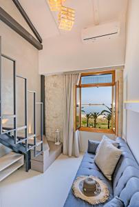 ein Wohnzimmer mit einem blauen Sofa und einem großen Fenster in der Unterkunft Mitos-Suites in Rethymno