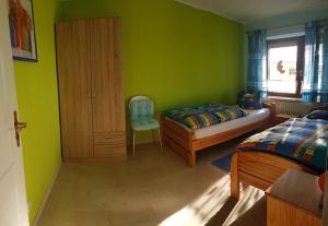 a bedroom with green walls and a bed and a chair at Haus Christine in Wremen