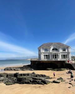 a white house on the beach with people on the sand at Port Pour Deux in Portrush