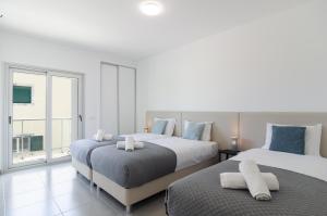 een slaapkamer met twee bedden en een groot raam bij Terraços Do Mar - Rooftop Pool with Sea View in Nazaré +49 foto's