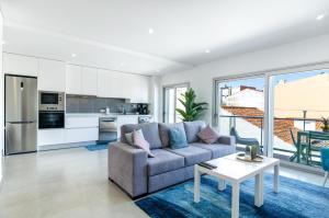 een woonkamer met een bank en een tafel bij Terraços Do Mar - Rooftop Pool with Sea View in Nazaré