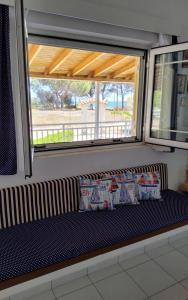 a bench in front of a window with pillows on it at Fully Equipped Beach House at Pachia Ammos Plytra in Plitra