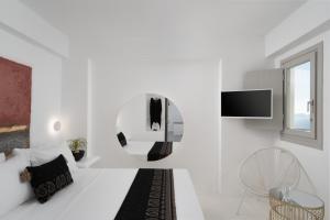 a white living room with a tv and a couch at Canyon Santorini in Fira