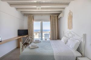 sypialnia z łóżkiem, telewizorem i oknem w obiekcie Elma’s Summerhouses w mieście Mykonos