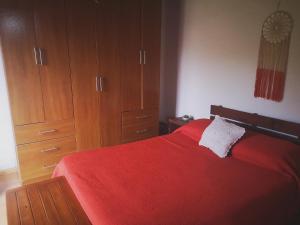 1 dormitorio con cama roja y armarios de madera en Adorable microcasa a 4km del centro de Maldonado y de playa mansa, en barrio muy tranquilo!, en Maldonado