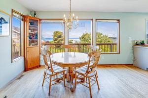 a dining room with a table and chairs and windows at Bayocean Retreat in Cape Meares