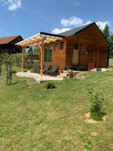 a wooden house with a roof on a field at Hillside Bio Resort Delux Apartments in Šešče pri Preboldu