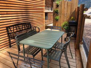 a green table and chairs on a wooden deck at Appartements Chalet Le Fornay in Morzine