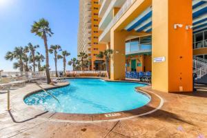 a swimming pool in front of a building with palm trees at Splash Condo, Aqua Park, Lazy River in Panama City Beach