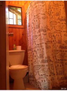 a bathroom with a toilet and a shower curtain at Cabañas Boutique - El Renegado Y Rustica in Recinto