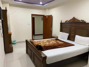 una camera con un grande letto con testiera in legno di Hotel Continental a Islamabad