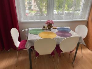 une table avec des chaises blanches et une table avec des assiettes colorées dans l'établissement Apartment Fialka, à Olomouc