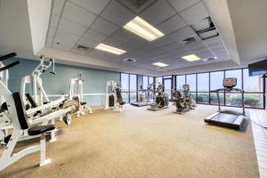 een fitnessruimte met loopbanden en machines in een kamer met ramen bij The Phoenix V Resort in Orange Beach