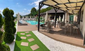 un resort con piscina e patio con sedie e ombrelloni di Pensiunea Alexandra & SPA a Divici