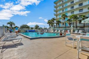 una piscina in un resort con sedie e persone di Atlantic Sands Condos a Cocoa Beach