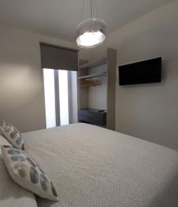 a bedroom with a bed and a flat screen tv at MiBu House in Palazzolo Acreide