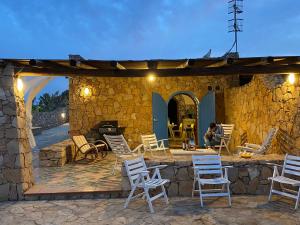 a patio with white chairs and a stone wall at Sitari Villa Lampedusa in Lampedusa