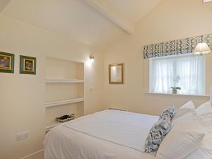 a bedroom with a white bed and a window at Reynard Ing Cottage in Addingham