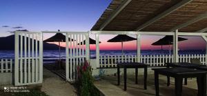 patio ze stołami i parasolami na plaży w obiekcie Karaburun Sunset Beach w mieście Orikum