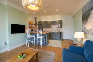 ein Wohnzimmer mit einem blauen Sofa und einer Küche in der Unterkunft Tradewinds in Weymouth