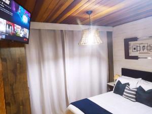 a bedroom with a bed and a television in it at Canquerini Chalés in Monte Verde