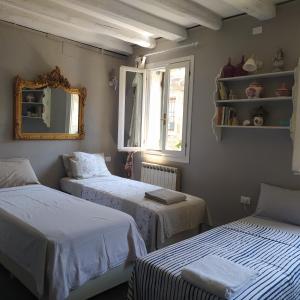 two beds in a room with a mirror and a window at Rio Marin Apartment Gondola View & Patio in Venice