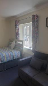 a bedroom with a bed and a couch and a window at SUNSHINE ROOM in Colchester
