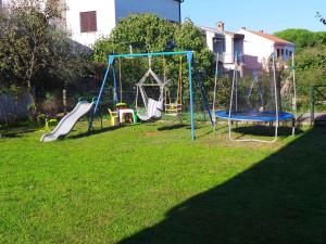 a yard with a playground with a slide and swings at Apartment Valbandon 9 in Fondole