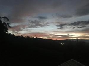 una puesta de sol sobre una colina con un cielo nublado en Sítio com belíssima paisagem para relaxar, en Cobras