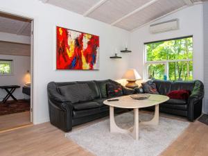 een woonkamer met een zwarte leren bank en een tafel bij 6 person holiday home in Glesborg in Fjellerup Strand