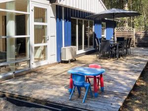 una terraza con sillas, una mesa y una sombrilla en 8 person holiday home in Hadsund, en Odde