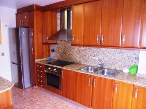 cocina con armarios de madera, fregadero y nevera en Maestrat, en Peñíscola