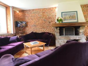 a living room with purple couches and a brick wall at house listed as an historic building near Montreuil in Gouy-Saint-André