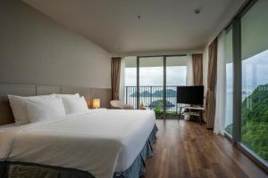 a hotel room with a large bed and a large window at Flamingos Cat Ba Resort luxury in Hai Phong
