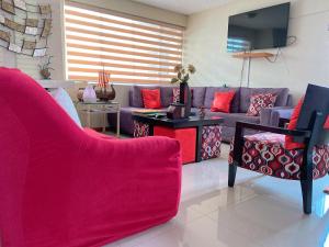 a living room with a purple couch and red pillows at Bed and Breakfast La Uvilla in Quito