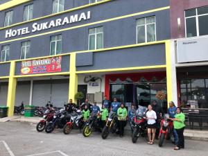 a group of people standing in front of a hotel with their motorcycles at HOTEL SUKARAMAI in Kampung Gurun