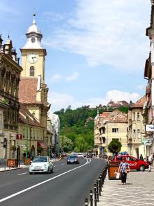 a city street with a clock tower and cars on the road at CERO Brasov in Braşov