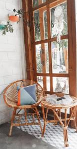 einen Korbstuhl neben einem Tisch und einem Fenster in der Unterkunft KALINDA HOMEY in Karimunjawa